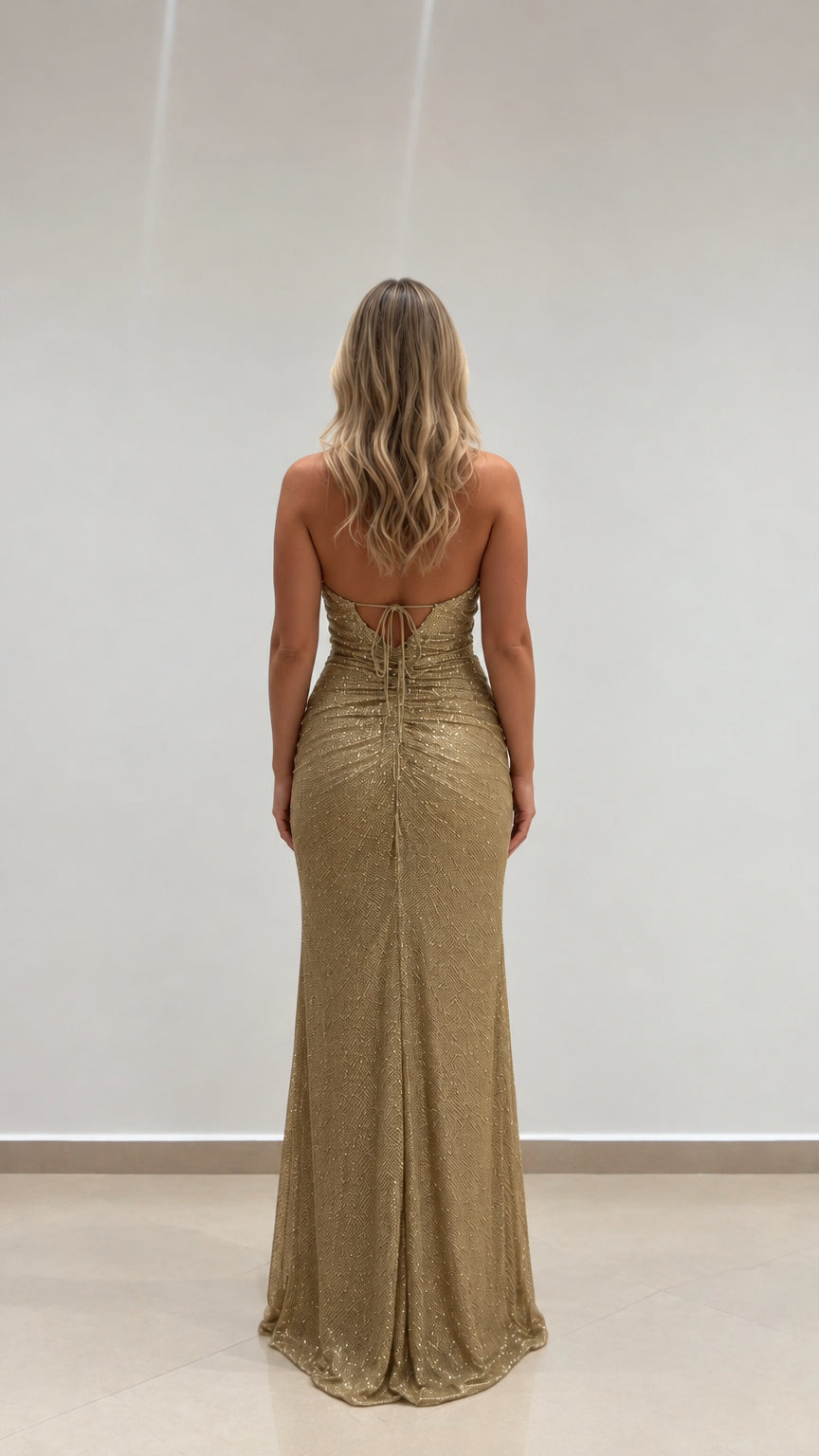 Rear view showcasing open lace-up back of gold formal evening gown