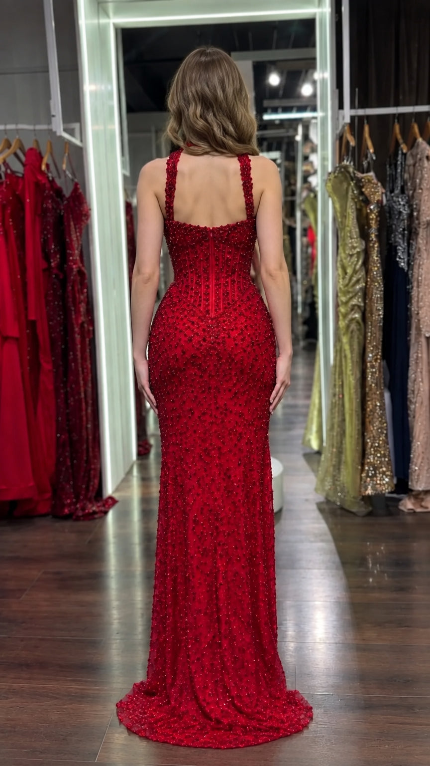 Back view of model in a red fitted floor-length beaded evening dress
