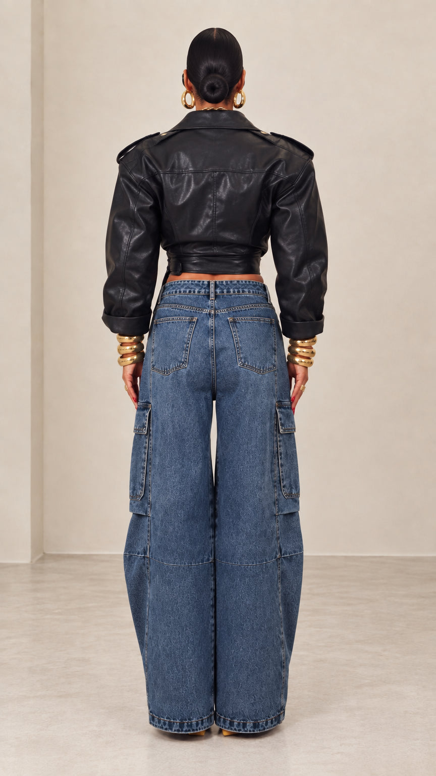 Back view of model wearing black cropped faux leather wrap jacket with structured shoulders
