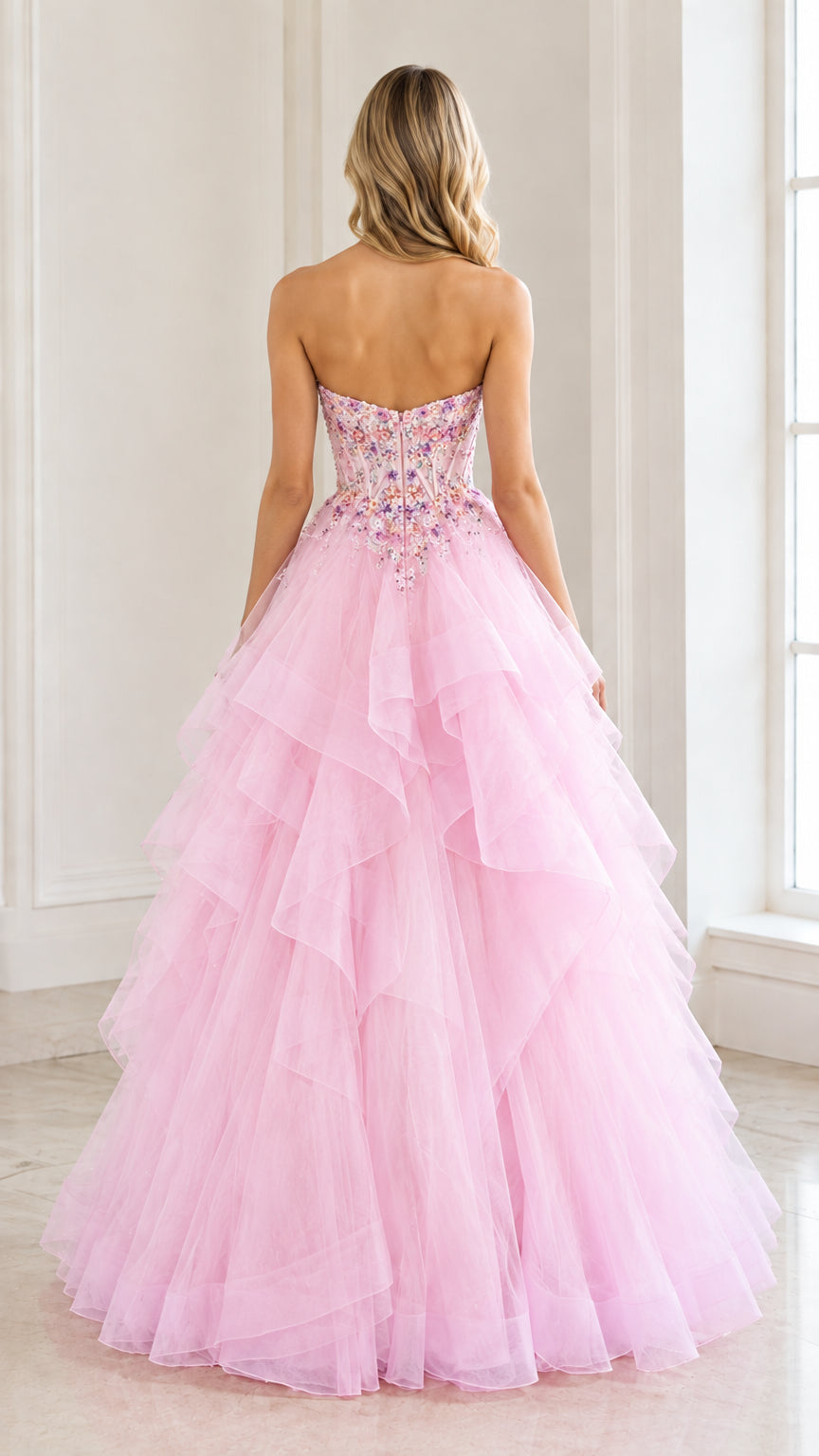 Back view of woman wearing a strapless pink formal ball gown with tiered tulle skirt