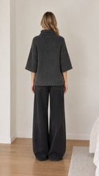 Back view of model wearing dark grey half sleeve turtleneck pullover sweater