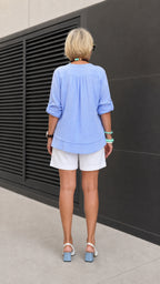 Back view of model showing curved back hem of Light Blue tunic top
