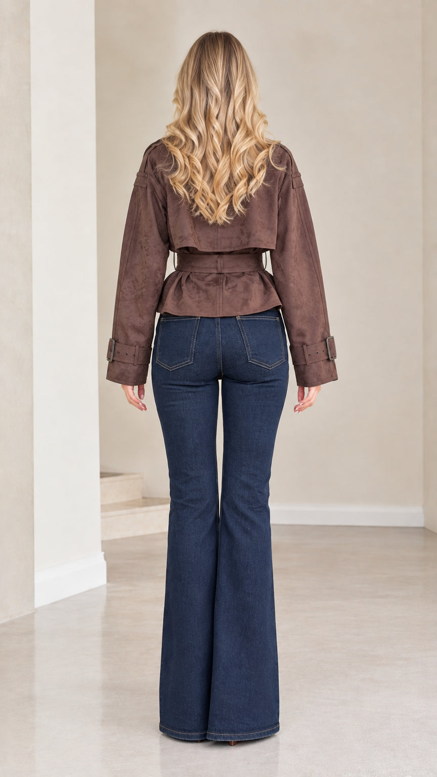 Back view of model wearing brown cropped trench jacket with waist belt
