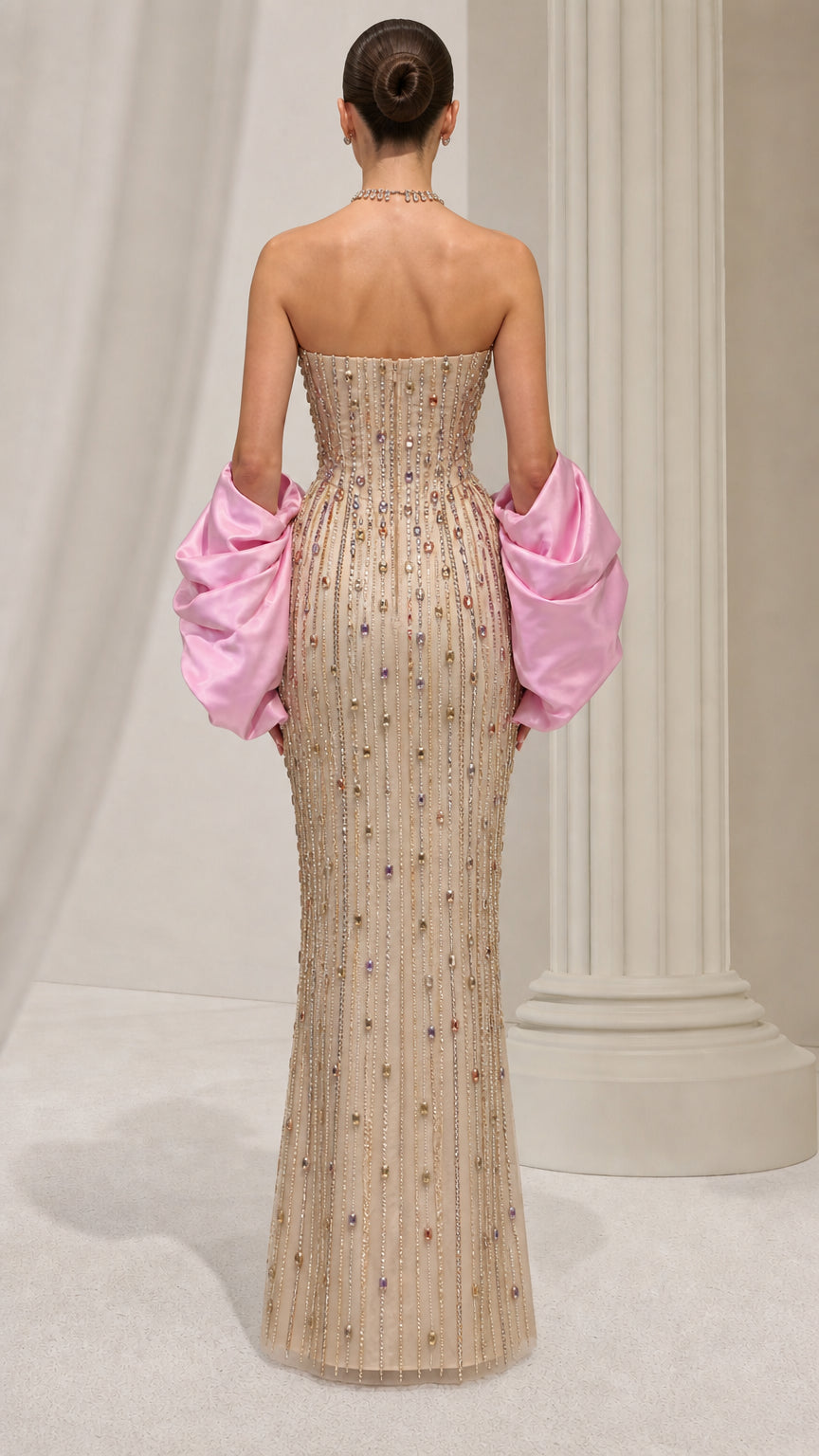 Back view of model in champagne embellished strapless evening gown with pink sleeve cuffs