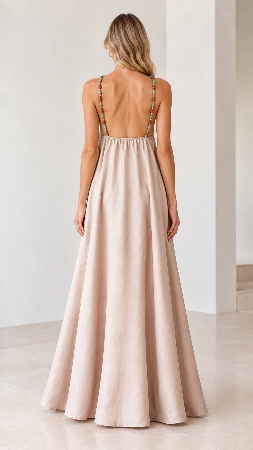 Back view of model showing open back and beaded straps on beige maxi dress