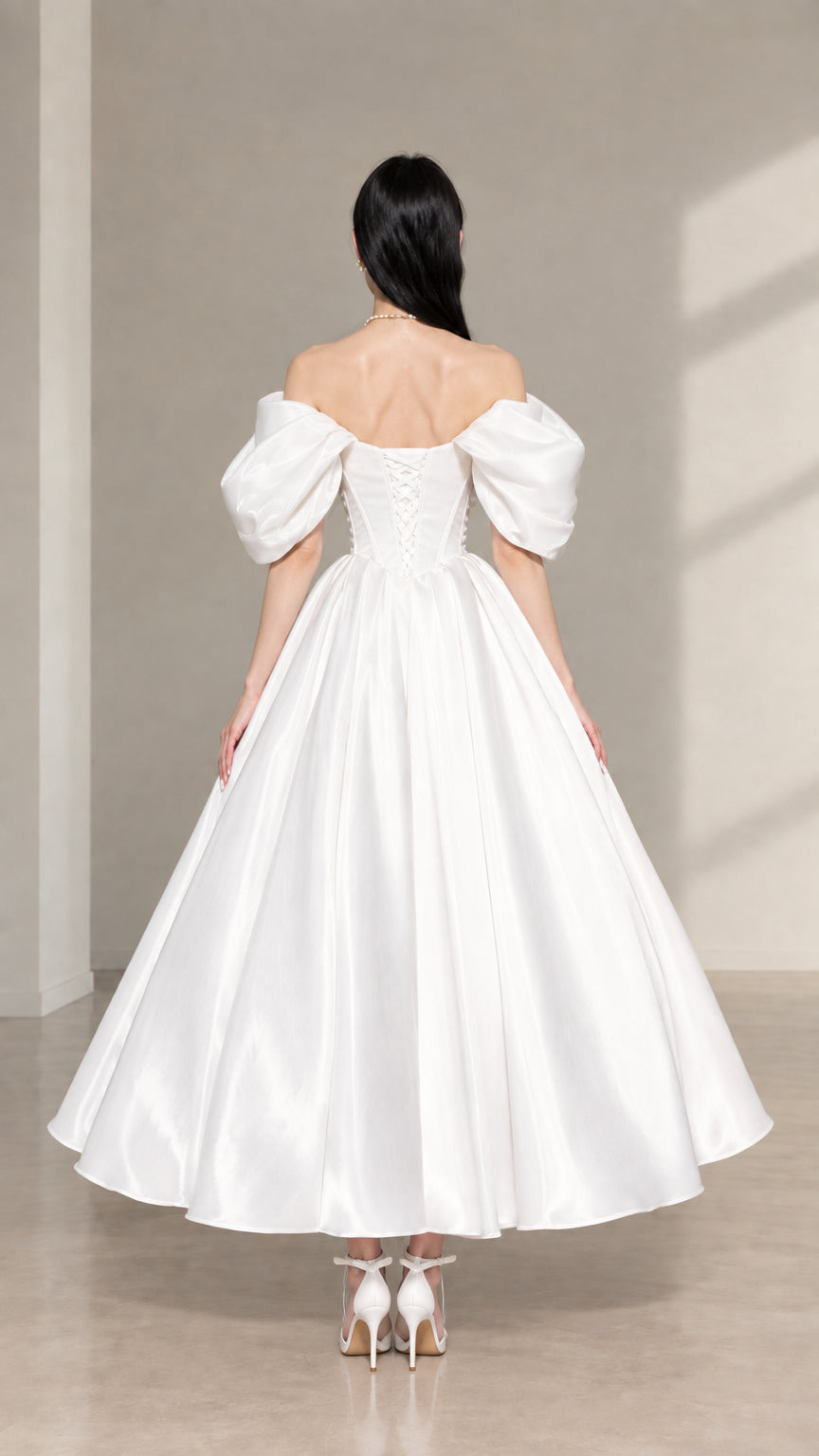 Back view of white satin corset midi dress featuring lace-up back detailing