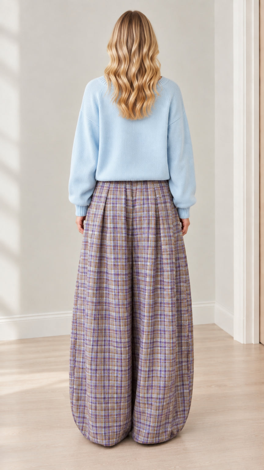 Back view of model showcasing the relaxed fit of the light blue sweater and balloon plaid pants