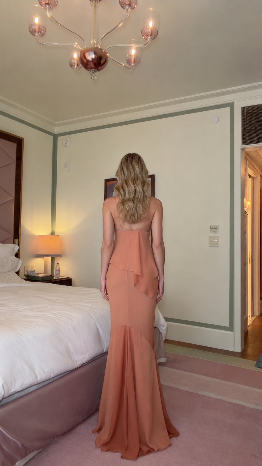 Back view of woman wearing dusty peach spaghetti strap evening dress with draped peplum