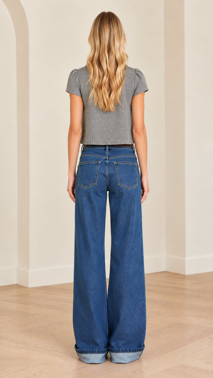 Back view of woman wearing gray fitted crop top paired with denim trousers