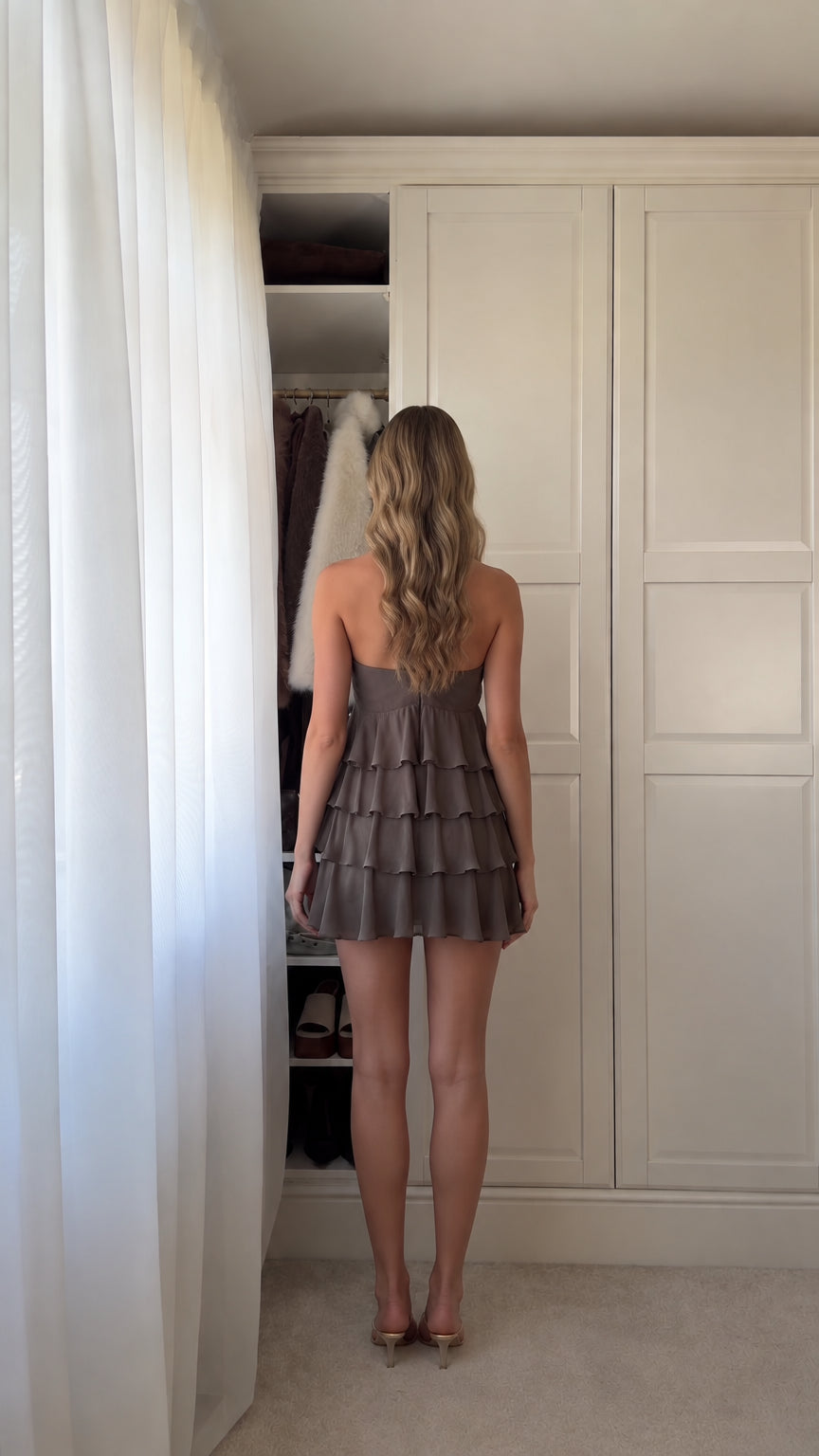 Back view of woman wearing halter neck ruffled mini dress showing open back