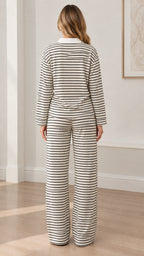 Back full view of woman wearing white striped polo top and wide leg trousers