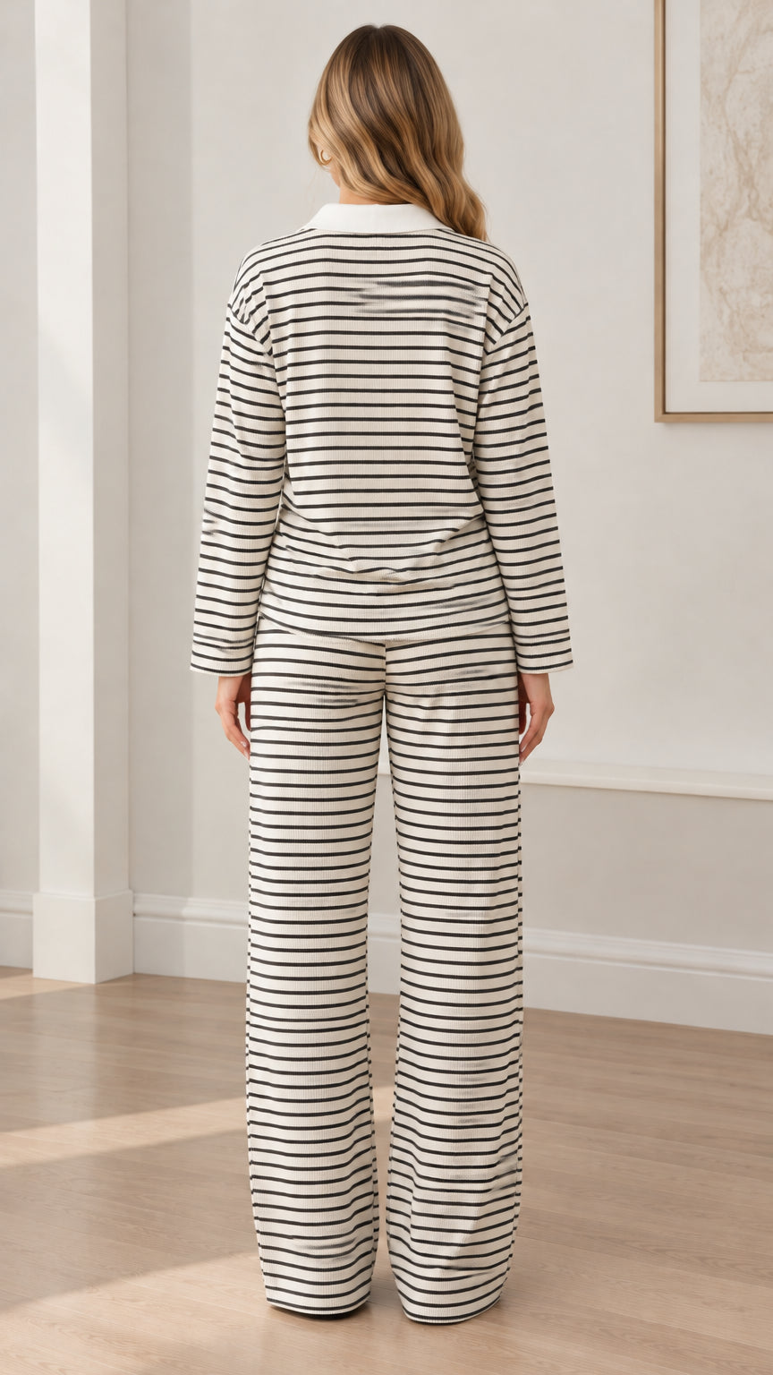 Back full view of woman wearing white striped polo top and wide leg trousers