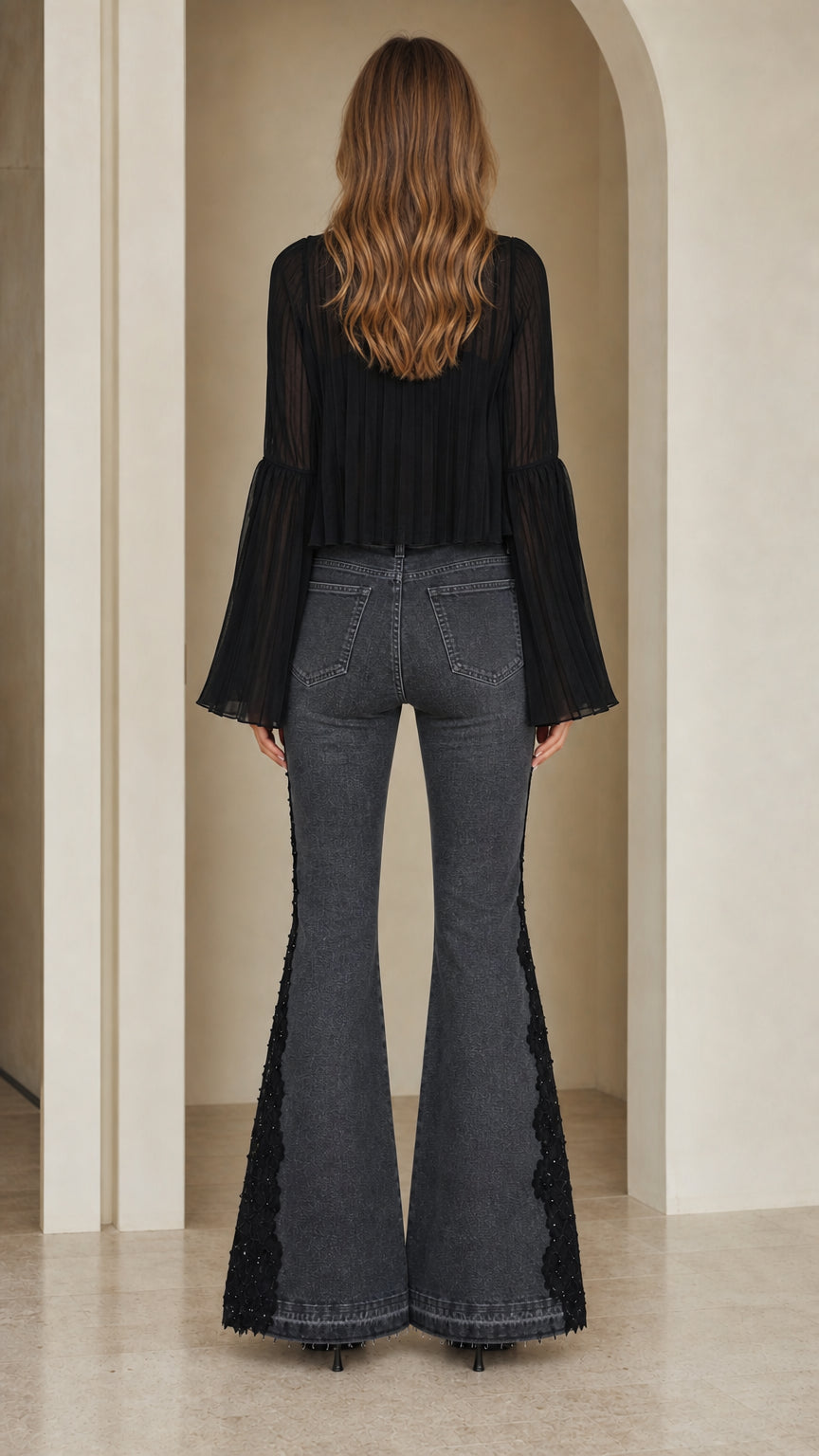 Back view of model wearing washed black lace embellished bell bottom jeans