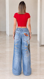 Back view of woman in red crop top and graphic printed wide-leg denim pants