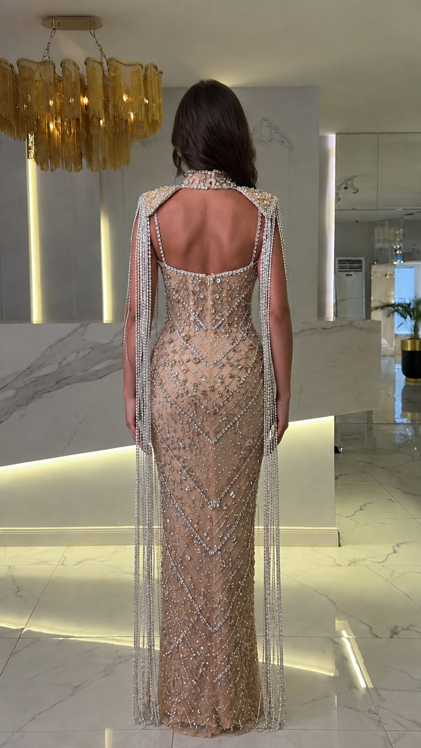 Back view of champagne formal evening dress showing open back design and beaded capelet