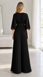 Back view of model showcasing the pleated back bodice and skirt of the black maxi dress
