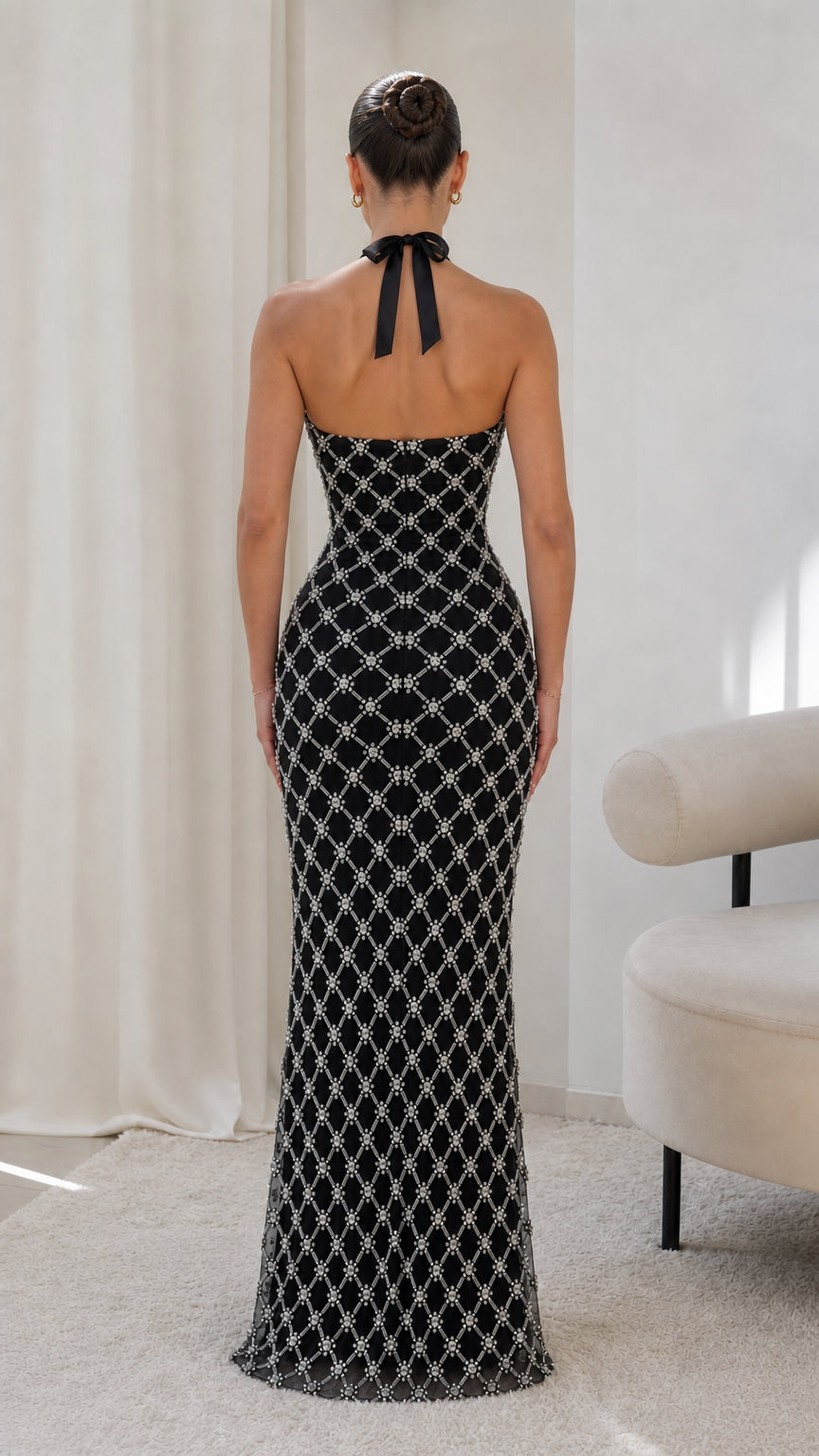 Back view of model showing open back and tie neck of black embellished dress