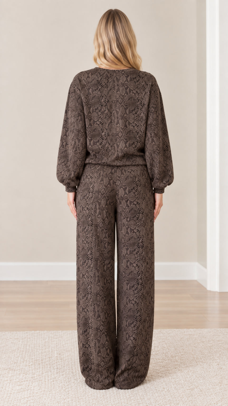 Back view of model wearing brown snakeskin print crewneck sweatshirt and wide leg pants