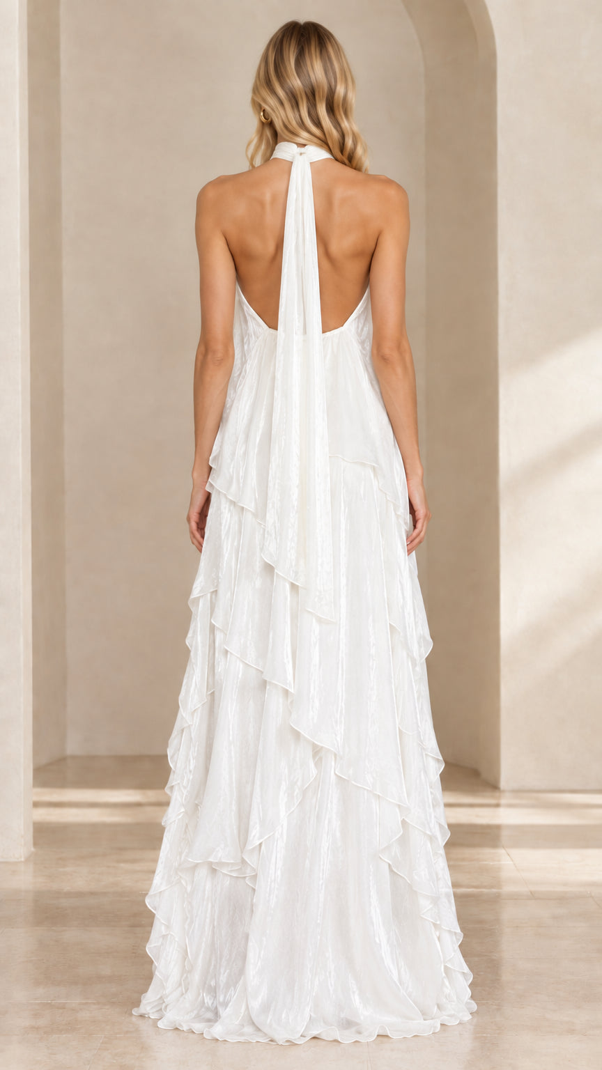 Back view of woman showcasing the open back and tie halter detail of the white maxi gown