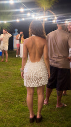 Back view of model in white backless halter disc sequin mini dress