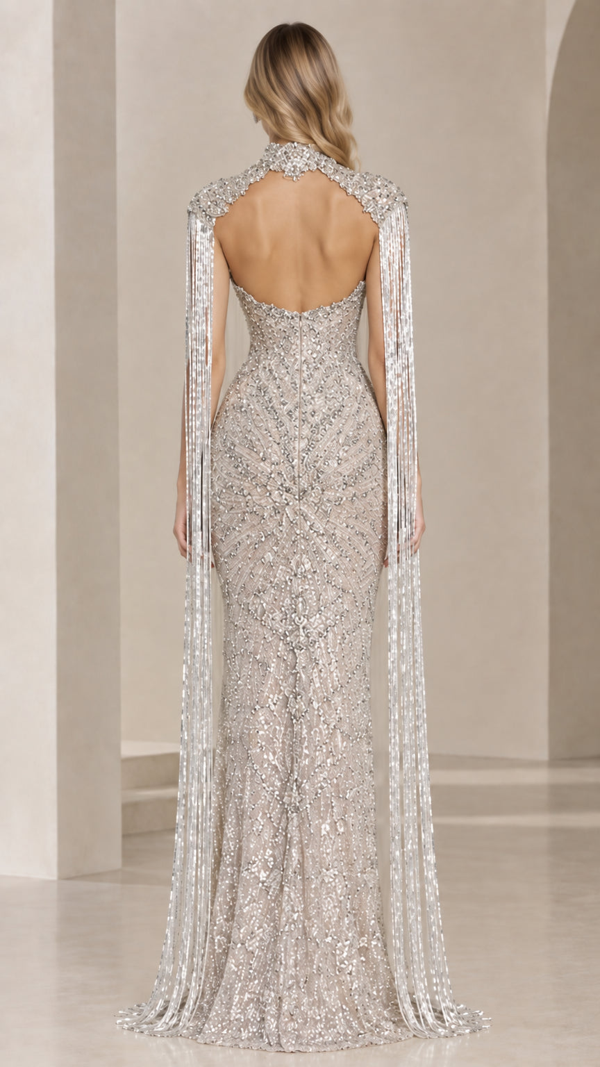 Back view of silver evening gown highlighting the dramatic open-back design and floor-length cape fringe
