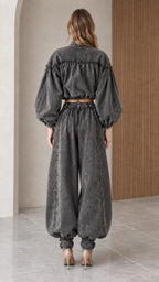 Back view of model highlighting the blouson back construction and high-rise elasticized denim trousers