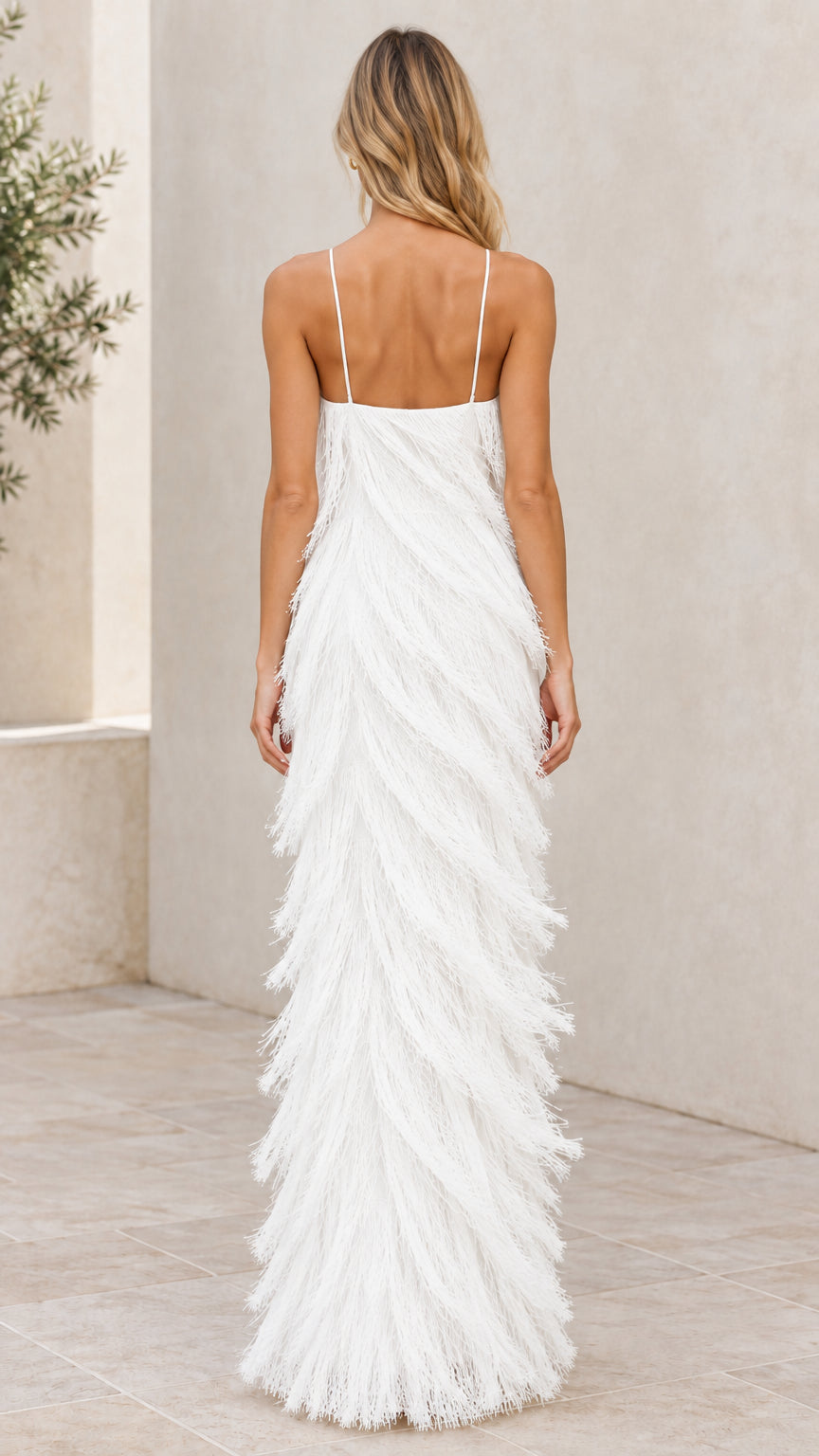 Back view of woman wearing white spaghetti strap fringe maxi dress