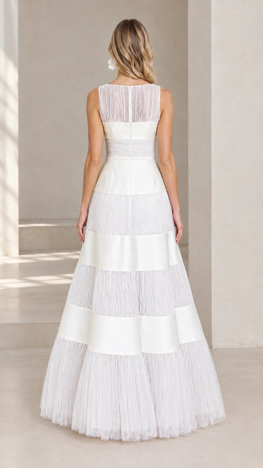 Back view of model wearing white sleeveless evening gown showing sheer illusion back