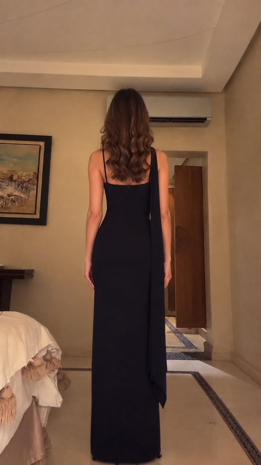 Back view of black sleeveless evening gown with low back and trailing scarf