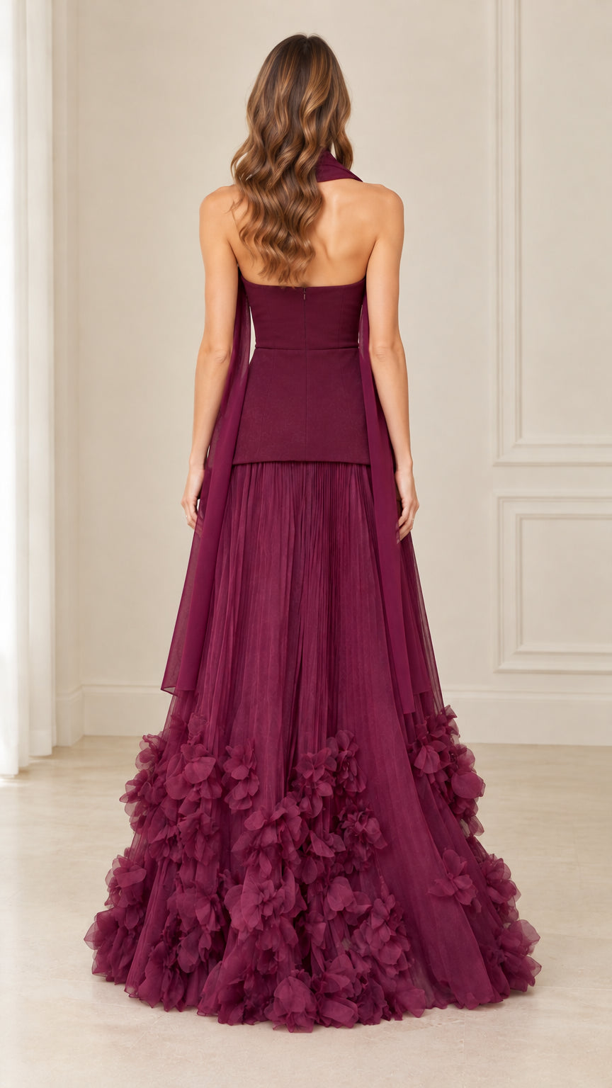 Back view of model in burgundy strapless peplum gown displaying the trailing neck scarf and fitted back bodice