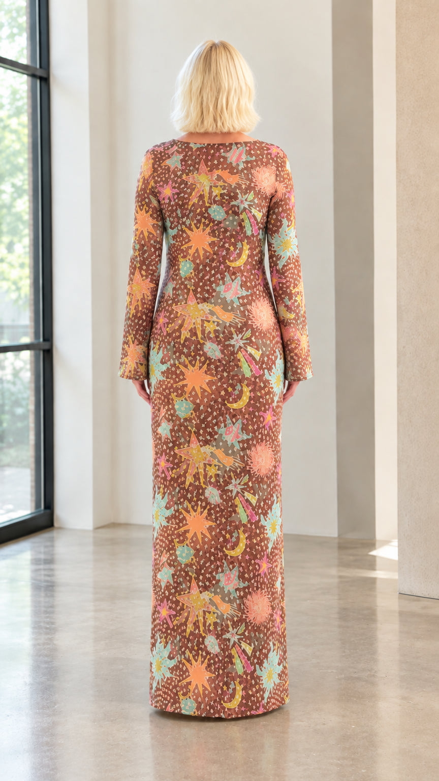 Back view of model wearing floor-length brown celestial printed long sleeve dress