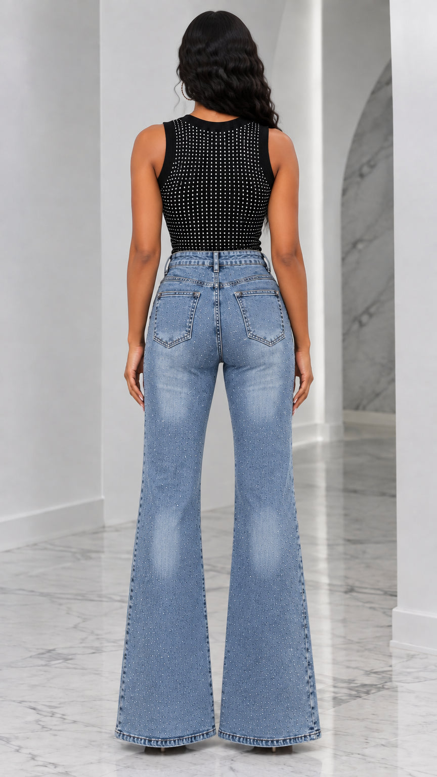 Back view of woman showing the fit of blue flare denim jeans and black sleeveless tank top