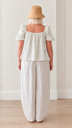 Back view of woman in white striped puff sleeve top and elastic waist lantern pants