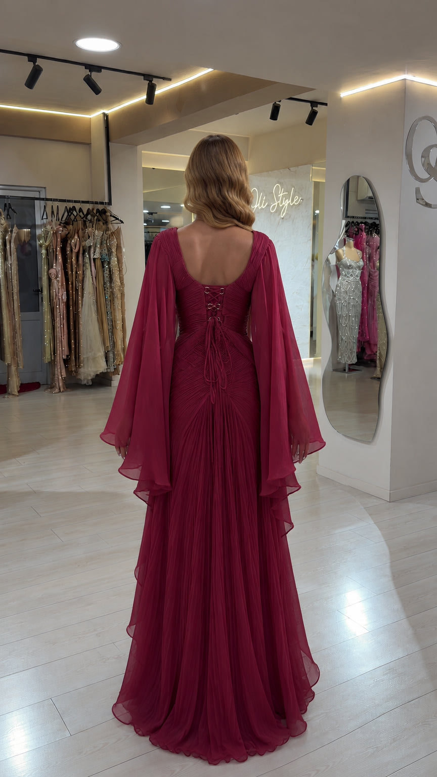 Rear view of burgundy evening gown displaying open lace-up back and draped cape sleeves