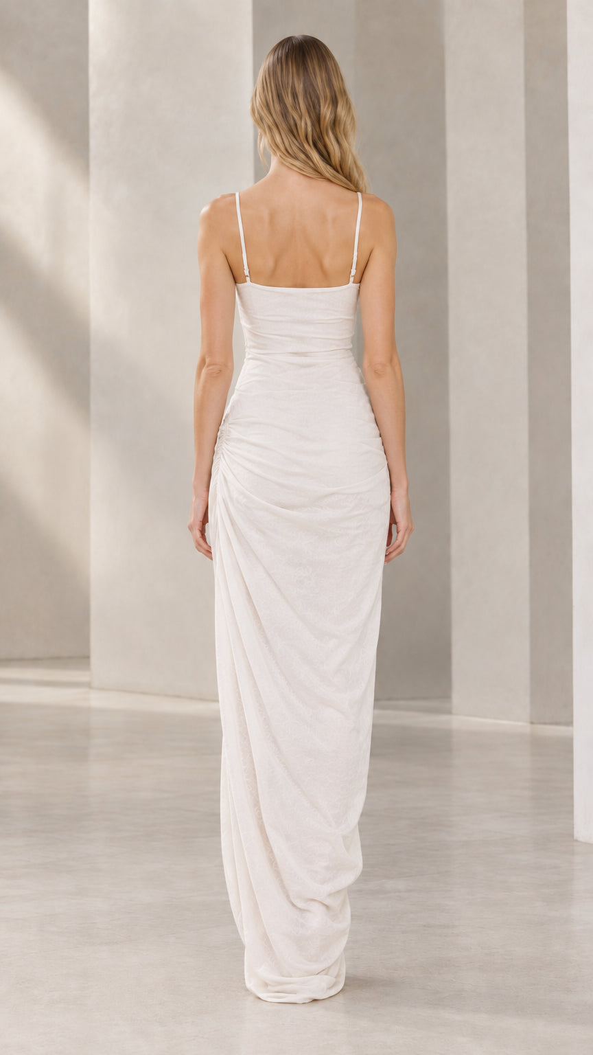 Back full-length view of model wearing white maxi slip dress with thin shoulder straps