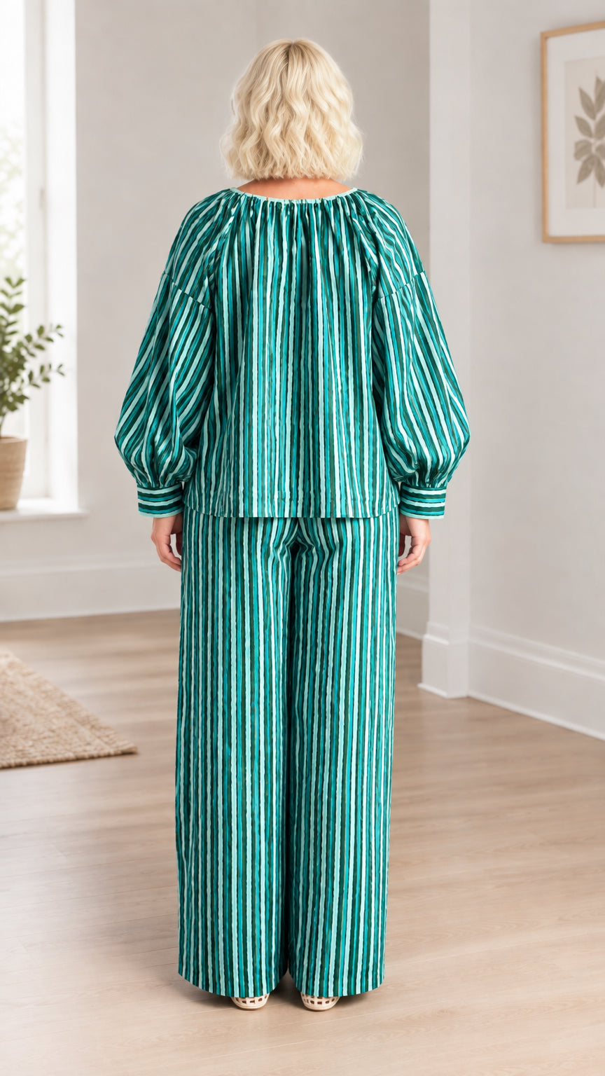 Back view of model showing green striped loose-fit blouse and matching flowing pants