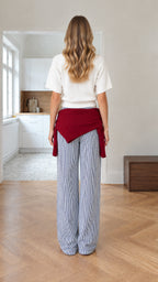 Back view of woman wearing white short-sleeve knit top and blue striped wide-leg trousers