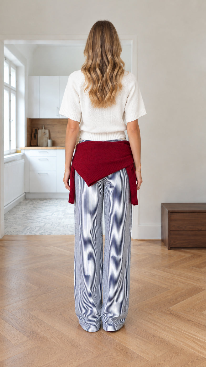 Back view of woman wearing white short-sleeve knit top and blue striped wide-leg trousers