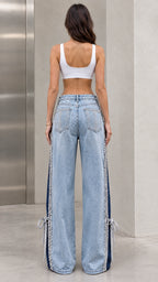 Back view of model wearing light blue embellished wide-leg jeans with crystal back pockets