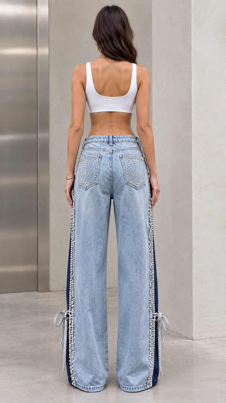 Back view of model wearing light blue embellished wide-leg jeans with crystal back pockets