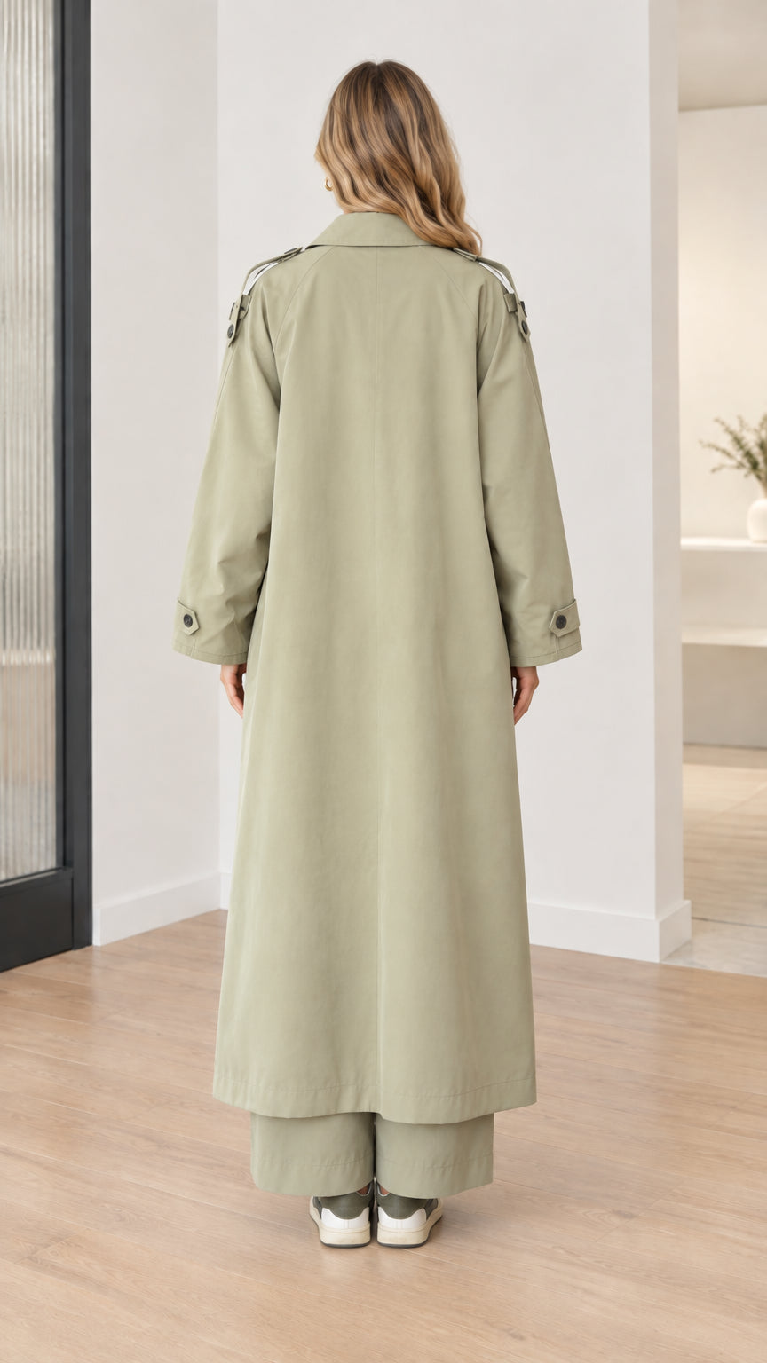 Back view of model wearing sage green maxi trench coat showing center vent