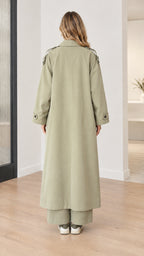 Back view of model wearing sage green maxi trench coat showing center vent