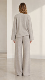 Back view of model wearing heather grey ribbed knit sweater and wide-leg trousers