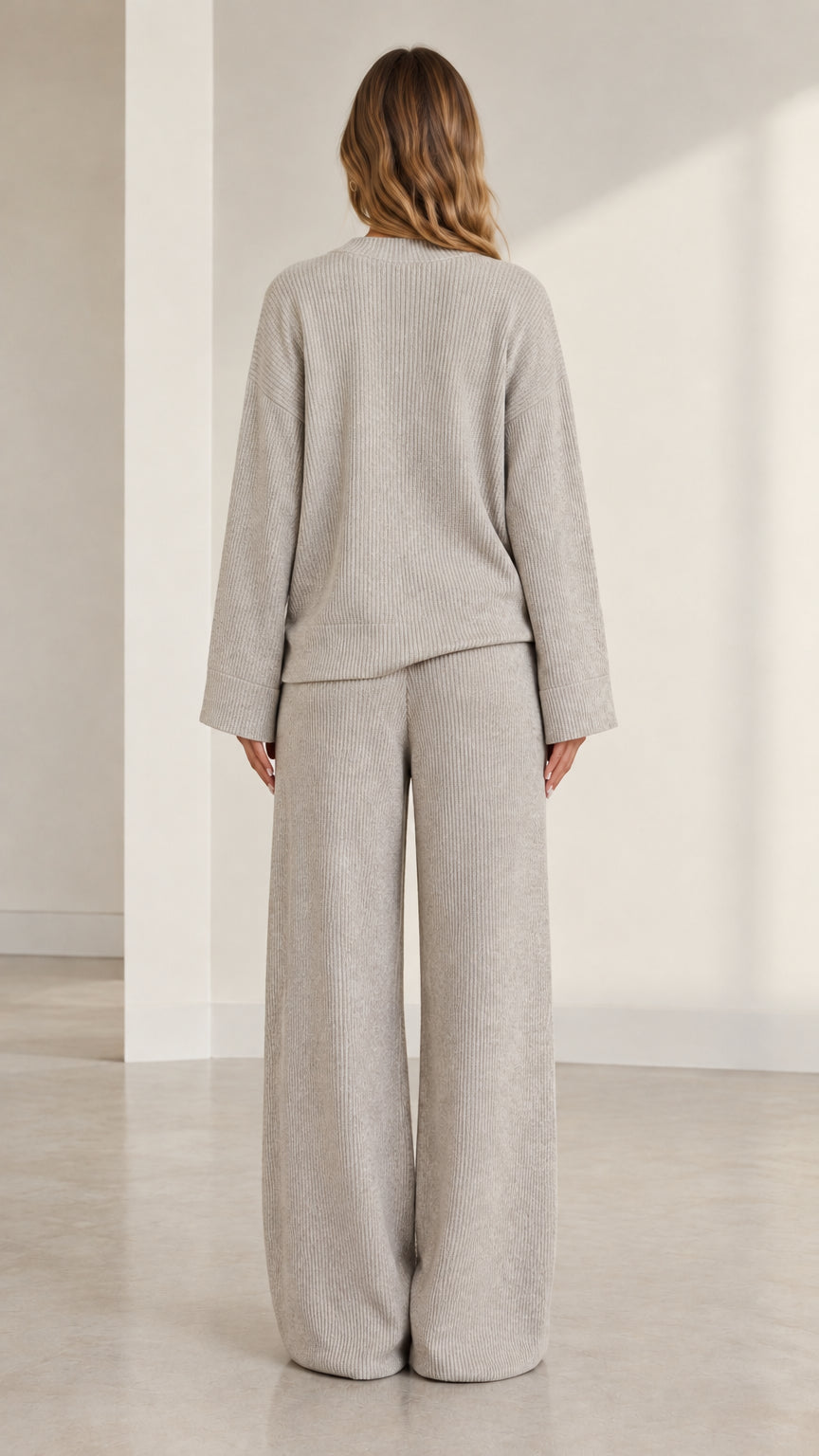 Back view of model wearing heather grey ribbed knit sweater and wide-leg trousers