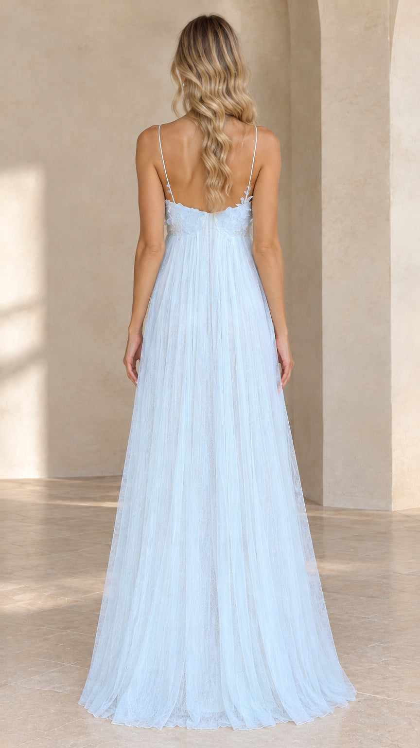 Back view of model showcasing open back and slim straps on light blue tulle maxi dress