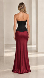 Back view of model showcasing black lace-up corset top and floor-length burgundy skirt