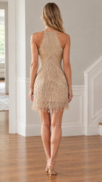Back view of model showcasing halter cut and beaded fringe on gold mini dress