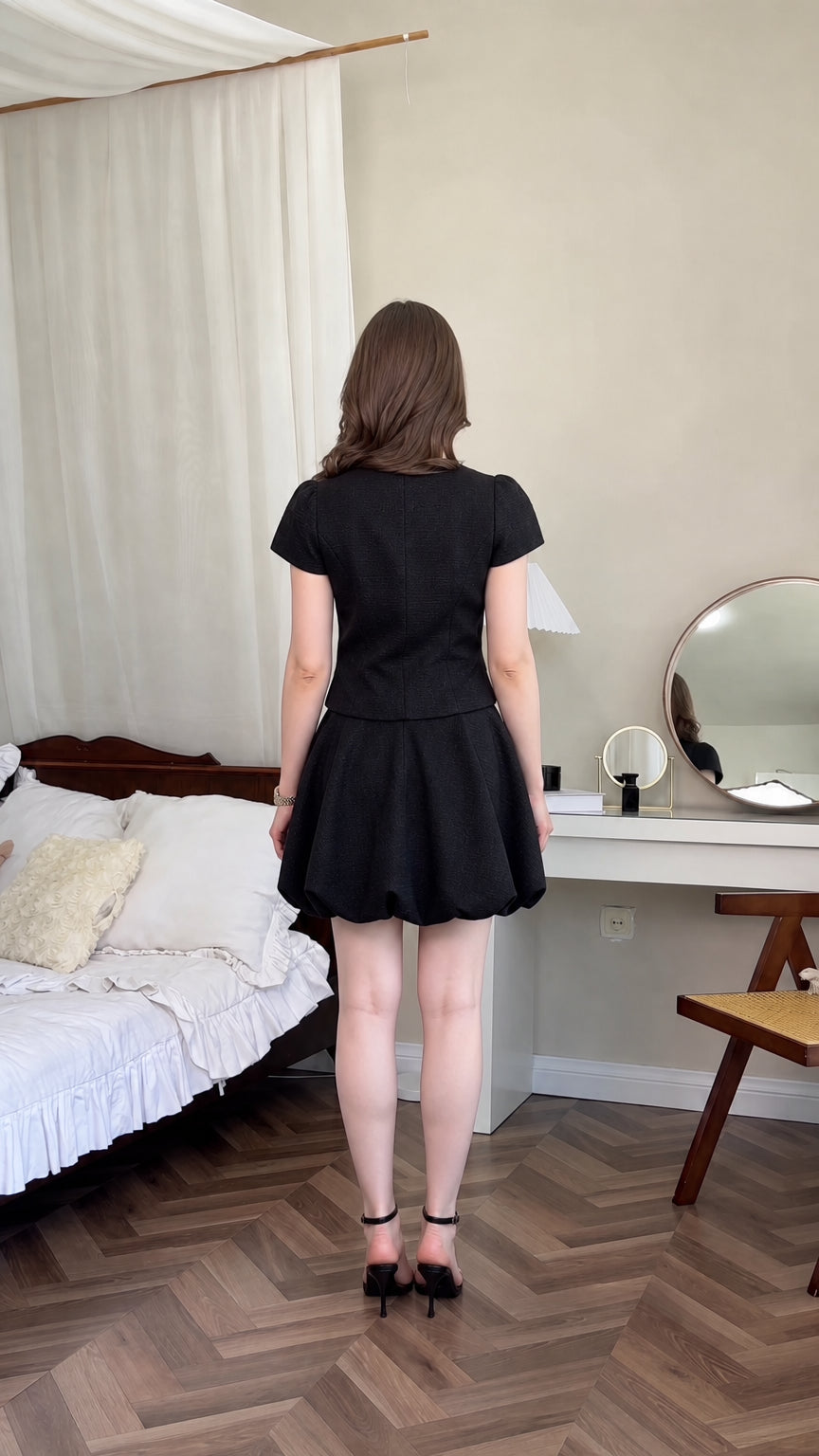 Back view of model wearing black short sleeve top and bubble hem mini skirt