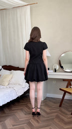 Back view of model wearing black short sleeve top and bubble hem mini skirt