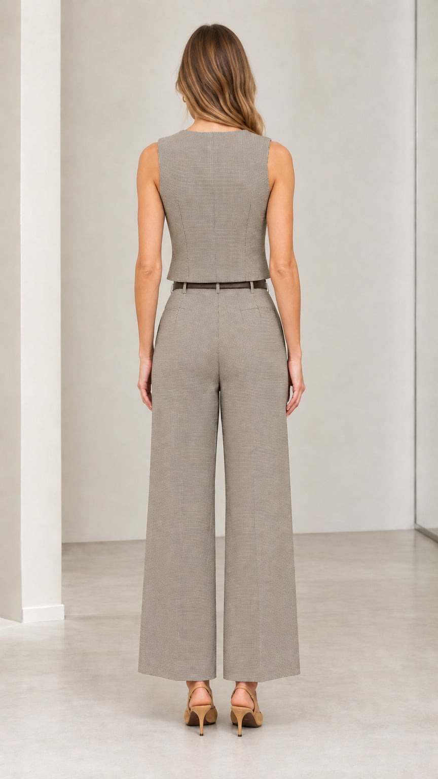 Back full-length view of model wearing grey checked sleeveless tailored vest and wide-leg pants